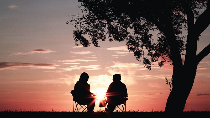 Retired Couple Bundled up Watching the Sunset Under a Tree