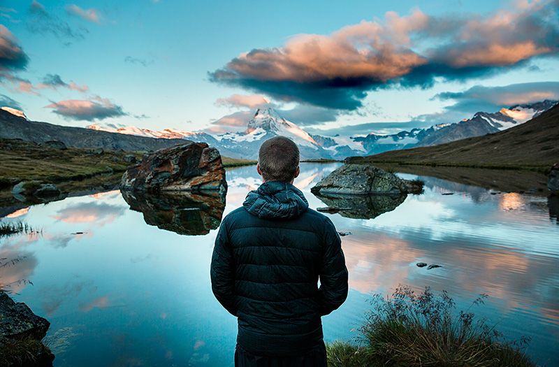 Man Looking Over Lake With Mountains in Background
