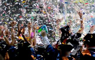 Grads in Cap and Gown Throwing Confetti