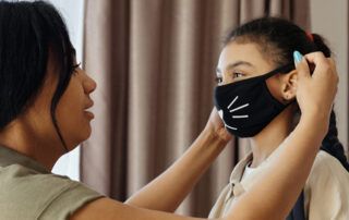 Parent Helping Child Put On Mask