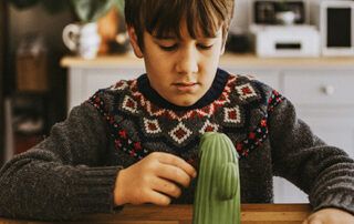 Child Putting Money in Piggy Bank