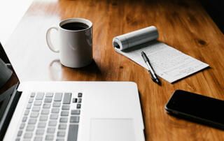 Computer, Coffee, Paper & Phone Sitting on Desk